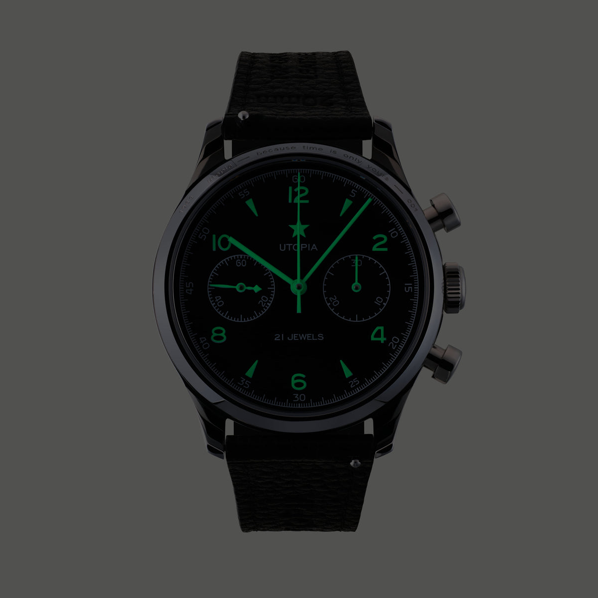 A black chronograph watch with a textured black strap, featuring glowing green hands, hour markers, and subdials on a dark gray background.