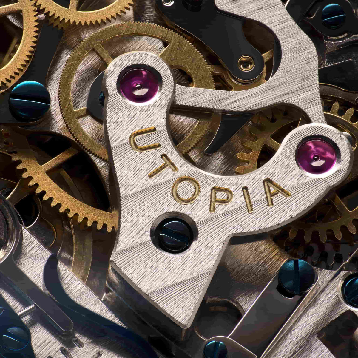 Close-up of a mechanical watch movement with interlocking gold-toned gears, brushed silver metal components, and purple jewel bearings. The word 'UTOPIA' is engraved on a central metal plate.