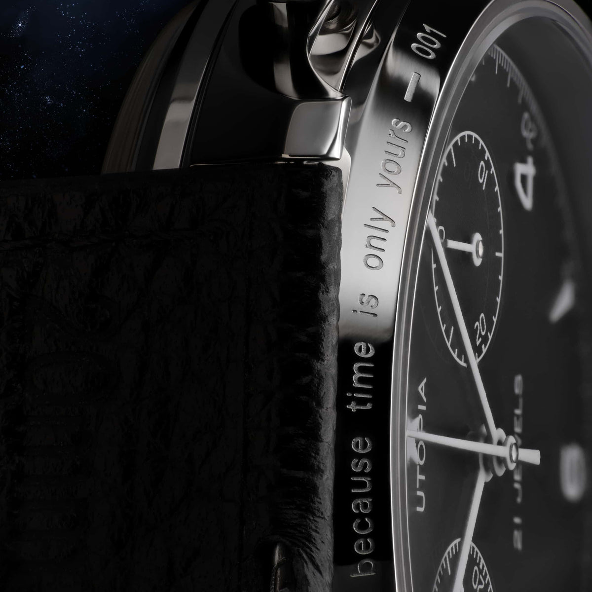 Close-up of a luxury watch featuring a black textured leather strap, a polished silver-tone stainless steel case, and a black dial with white markings and text.